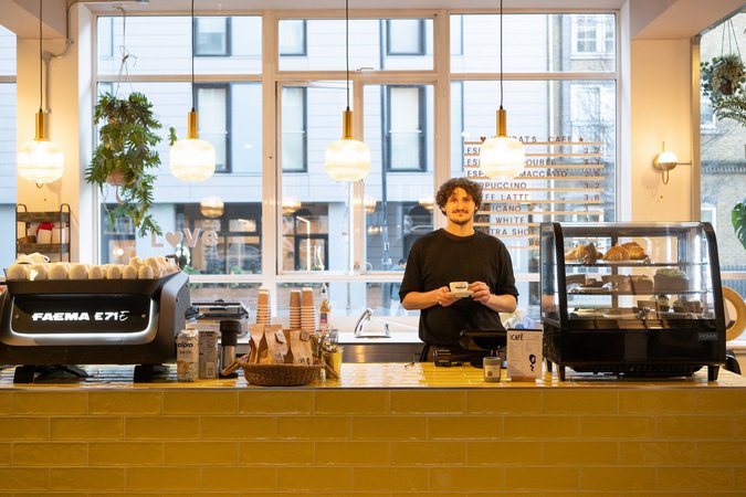 A focused barista prepares a coffee with precision at the WomCafé London