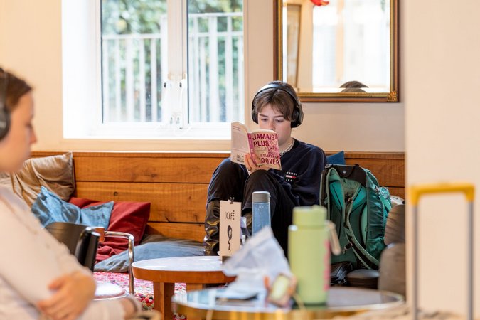 A traveler enjoys reading a book in the cozy seating area at WomCafé London