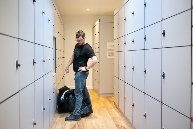 A guest accesses a large personal locker in a clean and well-maintained locker room at Wombat's City Hostel London