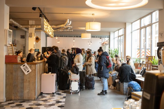 Travelers gather in the bustling lobby of Wombat's City Hostel London, surrounded by urban decor and a vibrant atmosphere