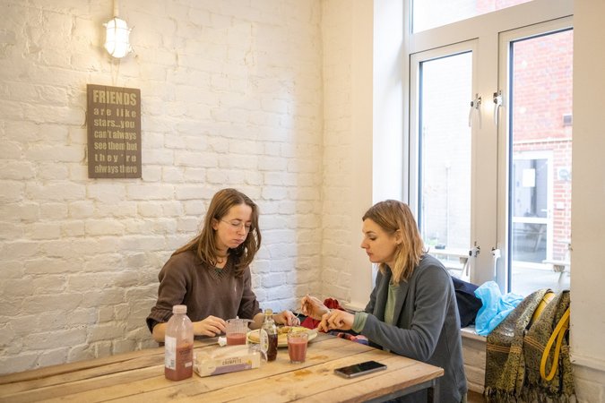 Two guests engaged in deep conversation while seated at a cozy café table inside Wombat's City Hostel London