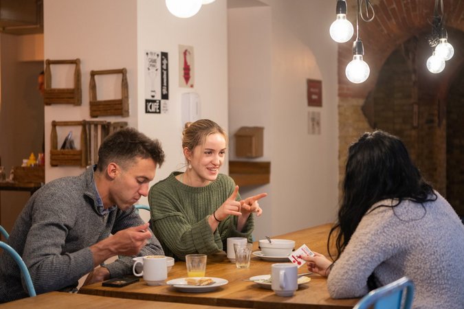 Guests engaged in friendly discussion over breakfast at a rustic table in Wombat's City Hostel London.